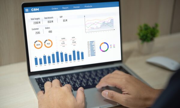 Man using computer laptop software with graphs and charts showing sales data. CRM Customer
